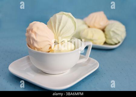 De délicieux guimauves d'air frais multicolores se trouvent sur une table de service dans des soucoupes Banque D'Images