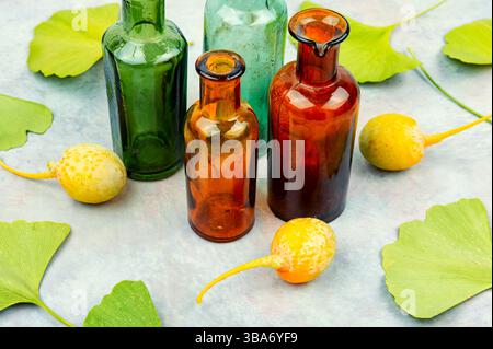 Pot en verre avec extrait du ginkgo avec des feuilles et des noix jaunes. Banque D'Images
