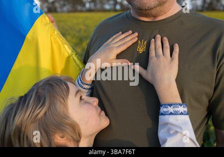 Paumes d'enfants autour de l'emblème national - trident, brodé sur le T-shirt des hommes. Fierté et patriotisme. Protection militaire pour les Ukrainiens. La paix pour U Banque D'Images