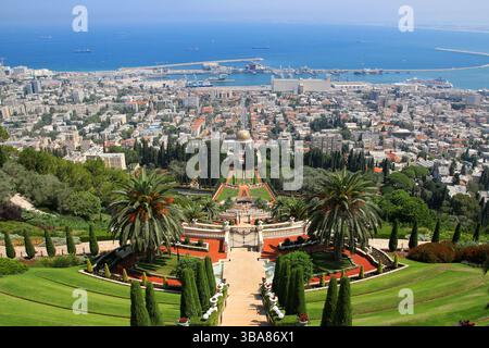 Vue panoramique sur les jardins Bahá’í et le Sanctuaire du Báb à Haïfa, Israël, avec le paysage urbain, le port de Haïfa et la mer Méditerranée bleue par une journée ensoleillée. Banque D'Images