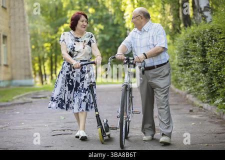 Heureux couple âgé avec un vélo. Beau homme et femme aînés. Mari et femme en vieillesse dans le parc Banque D'Images