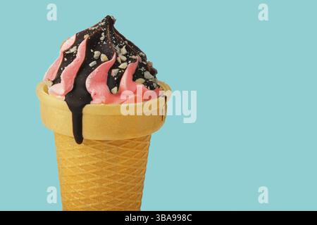 Crème glacée. Crème glacée rose sucrée dans un cône de gaufre versé avec du chocolat sur un fond turquoise.joli dessert Banque D'Images