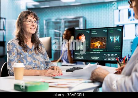 Patiente senior prenant les données des antécédents médicaux avec les résultats des tests et autres dossiers de soins de santé, prenant le rapport de diagnostic de son médecin à la clinique. Discutez d'un plan de reprise. Banque D'Images