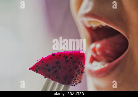 Gros plan d'une personne mangeant de délicieux fruits frais du Dragon rouge Banque D'Images