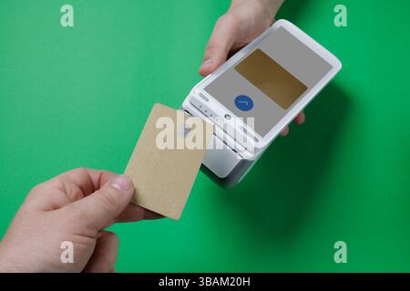 Paiement sans contact à l'aide d'une carte de crédit en or sur un terminal sans fil sur fond vert, concept fintech moderne. Banque D'Images