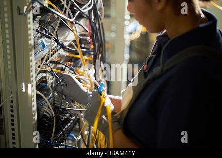 Technicien connectant les câbles réseau dans la salle des serveurs Banque D'Images