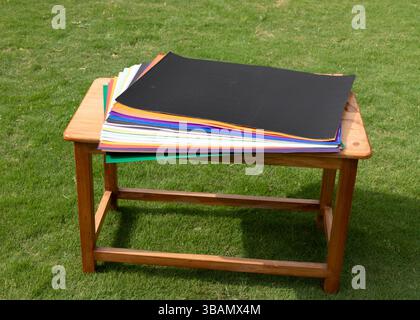 Papiers de carte artisanale colorés étalés sur une table en bois. Décors d'art et de photographie. Banque D'Images