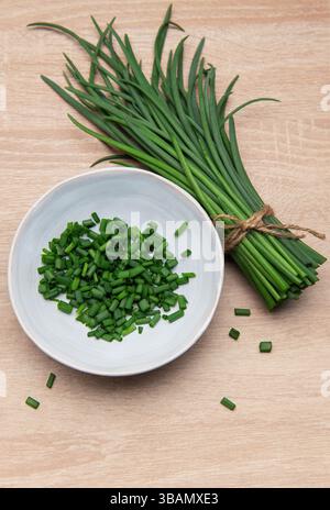 Ciboulette fraîche groupée et hachée dans un bol sur une surface en bois Banque D'Images