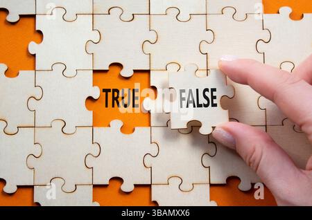 Symbole vrai ou faux. Mot concept vrai ou faux sur puzzle en bois. Main d'homme d'affaires. Beau fond orange. Business et vrai ou faux concept. Banque D'Images