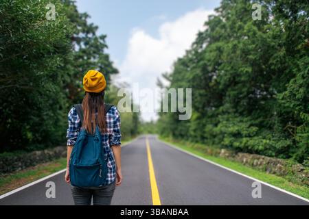 Une femme portant un béret jaune voyage avec un sac à dos. Photo de haute qualité Banque D'Images
