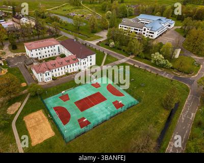 Vue aérienne des courts de tennis et des bâtiments scolaires dans un paysage verdoyant animé. Banque D'Images