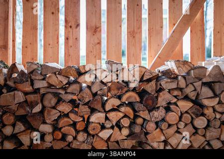 Grumes de bois de chauffage empilées stockées dans un hangar en bois pour l'hiver. Banque D'Images