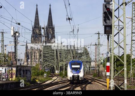 Trafic ferroviaire entre Cologne-Deutz et la gare centrale de Cologne. Pont Hohenzollern, pont ferroviaire sur le Rhin. Les tours de la cathédrale de Cologne en Banque D'Images