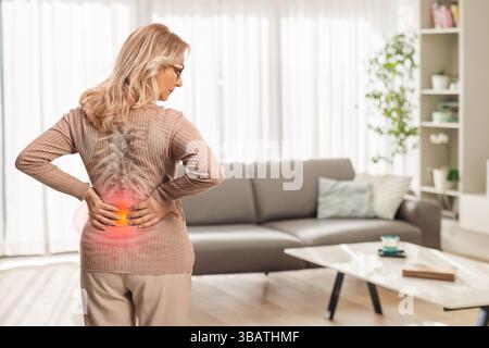 Vue arrière d'une femme d'âge moyen à domicile avec rachis raide Banque D'Images