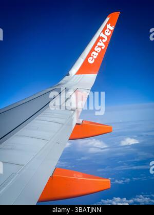 Surplombant les nuages à bord d'un Airbus A320 easyJet, cette vue époustouflante sur l'aile capture la beauté du vol par temps clair, avec un ciel bleu profond Banque D'Images