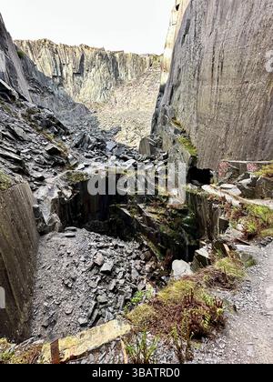 Murs d'ardoise et ardoise lâche sous un petit filet d'eau à la chute d'eau dans le centre de Dinorwic Quarry, Llanberis, au nord du pays de Galles. Banque D'Images