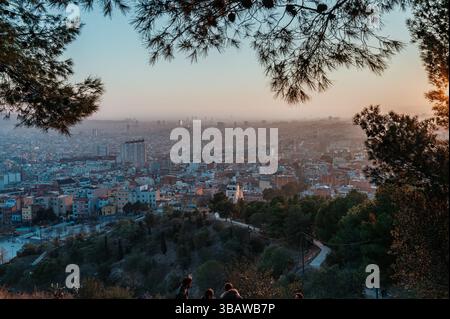 Touristes appréciant une vue imprenable sur le coucher du soleil sur le paysage urbain de barcelone depuis le point de vue de bunkers del carmel au crépuscule Banque D'Images
