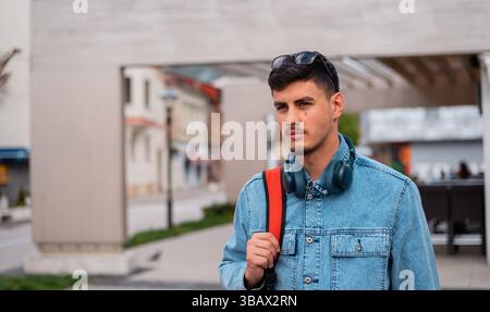 Un jeune homme élégant urbain marche dans la rue de la ville. Banque D'Images
