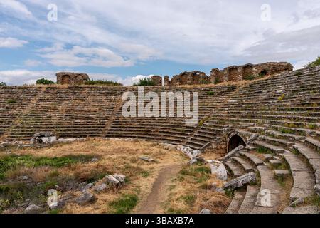 Ancien stade d'Aphrodisias, présentant des rangées de sièges voûtés et les vestiges d'une grande arène sportive, entouré de paysages accidentés. Banque D'Images