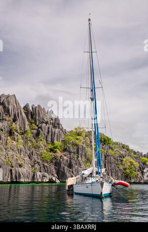 Un voilier à côté des roches calcaires près du lac Kayangan sur l'île de Coron, Philippines. Le lac Kayangan est un lac volcanique isolé dans le milieu de o Banque D'Images