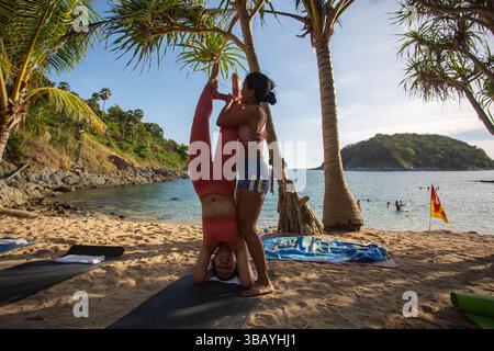 Groupe de femmes pratiquant le yoga sur la plage Yanui est une petite plage tranquille avec une mer bleue et une petite île en face qui est un magnifique coucher de soleil vue Banque D'Images