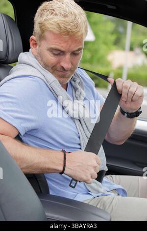 conducteur masculin enfilant sa ceinture de sécurité Banque D'Images