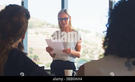 Gros plan d'une femme d'affaires donnant une présentation à l'équipe entreprises assise autour de la table dans le bureau moderne Banque D'Images