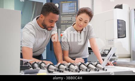 Ingénieurs hommes et femmes discutant des plans de travail tout en regardant l'ordinateur portable Banque D'Images