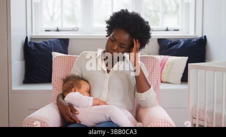 Nouvelle mère souffrant de dépression post-natale tenant la fille de bébé endormi dans la pépinière à la maison Banque D'Images