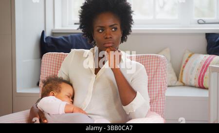 Nouvelle mère souffrant de dépression post-natale tenant la fille de bébé endormi dans la pépinière à la maison Banque D'Images