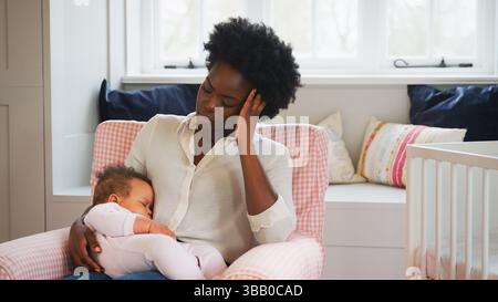 Nouvelle mère souffrant de dépression post-natale tenant la fille de bébé endormi dans la pépinière à la maison Banque D'Images