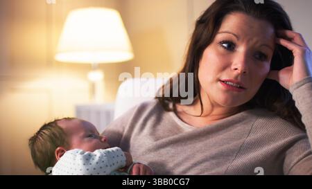 Nouvelle mère anxieuse souffrant de dépression post-natale tenant bébé garçon dans la pépinière à la maison Banque D'Images