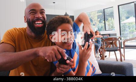Famille afro-américaine à la maison avec fils et père jouant au jeu vidéo ensemble Banque D'Images