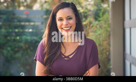 Portrait de jeune femme hispanique souriante dans Garden at Home Against Flaring Sun Banque D'Images