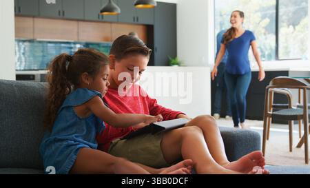 Les enfants jouant aux jeux vidéo sur la tablette numérique pendant la réunion de famille À la maison Banque D'Images