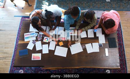 Vue du dessus de l'équipe ayant une réunion de conception créative autour de Wooden Table dans le bureau Banque D'Images