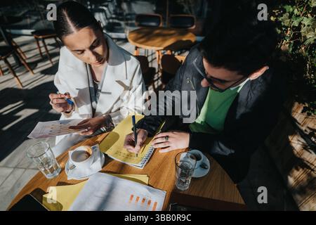 Jeune équipe de démarrage discutant des idées dans une réunion en plein air autour d'un café Banque D'Images