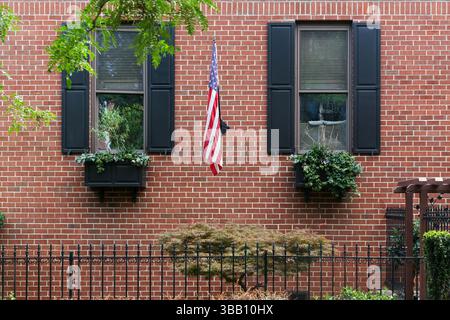 Philadelphie, États-Unis – 20 juillet 2013 : une maison de ville en brique avec des volets noirs, des boîtes de fenêtre et un drapeau américain dans une rue calme de Philadelphie. Banque D'Images