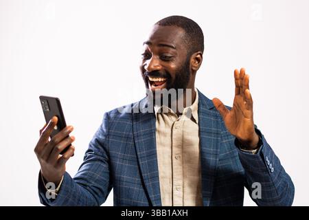 Portrait d'homme d'affaires heureux et prospère. Homme noir en costume d'affaires a un appel vidéo sur smartphone. Banque D'Images