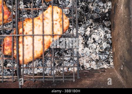 Des tons chauds et rustiques mettent en valeur le poulet parfaitement carbonisé, rayonnant un sentiment de cuisine maison et de plaisir délicieux, idéal pour les sites Web culinaires, le repos Banque D'Images