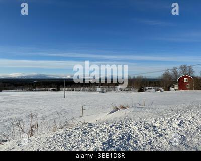 Un paysage hivernal serein avec une maison rouge nichée dans la neige Banque D'Images