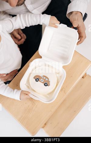 Petit gâteau au bento. avec une voiture. Mini gâteau sucré pour le garçon d'anniversaire. Gâteau glacé dans une boîte. Banque D'Images
