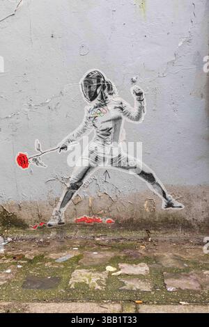 Street art de Montmartre : découpe en pâte de blé d'une escrimeuse avec une rose comme épée sur le mur de la rue André Antoine dans le 18e arrondissement de Paris, France Banque D'Images