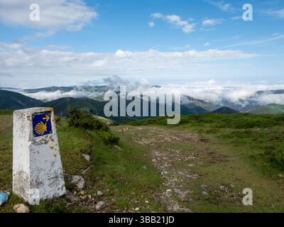 Jalon concret indiquant la voie à suivre pour les pèlerins marchant le Camino de santiago, avec un beau paysage de montagne en arrière-plan avec Banque D'Images