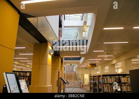 Intérieur lumineux de la bibliothèque publique à Manchester, avec des rangées de livres et un espace de lecture bien éclairé. Banque D'Images