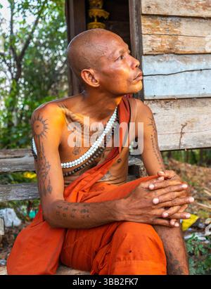 Cambodge-21 février 2024 : un Saint homme, vêtu de robes bouddhistes traditionnelles, est assis à l'extérieur de sa hutte, au pied du complexe du temple, à quelques miles au nord de Banque D'Images