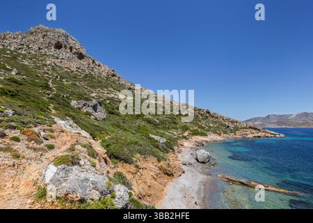 Paysage montagneux, accidenté et luxuriant, littoral et mer Égée sur l'île de Telendos en Grèce par une journée ensoleillée. Banque D'Images