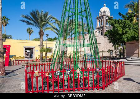 Arbre fait de guirlande scintillante verte comme décoration de Noël sur la place de la ville avec paroisse de notre-Dame de Loreto en arrière-plan, journée ensoleillée en Baja Californ Banque D'Images