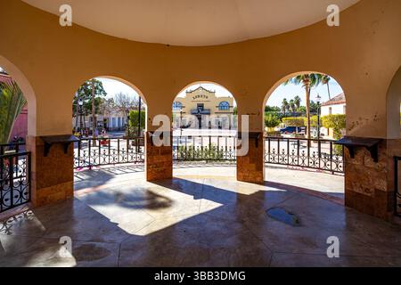 Place principale et palais du gouvernement vu de l'intérieur d'un kiosque, piliers, arches, garde-corps en métal, mur et toit jaune, journée ensoleillée à Loreto, Baja Cal Banque D'Images