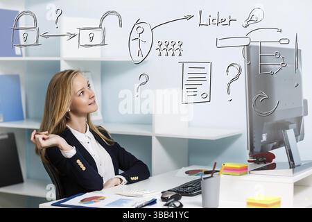 Jolie jeune femme d'affaires assis au bureau avec ordinateur de bureau bleu Banque D'Images